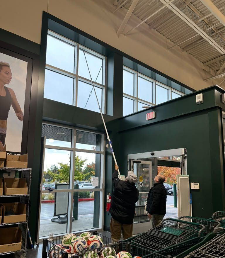 Crew cleaning high interior windows above a store entrance