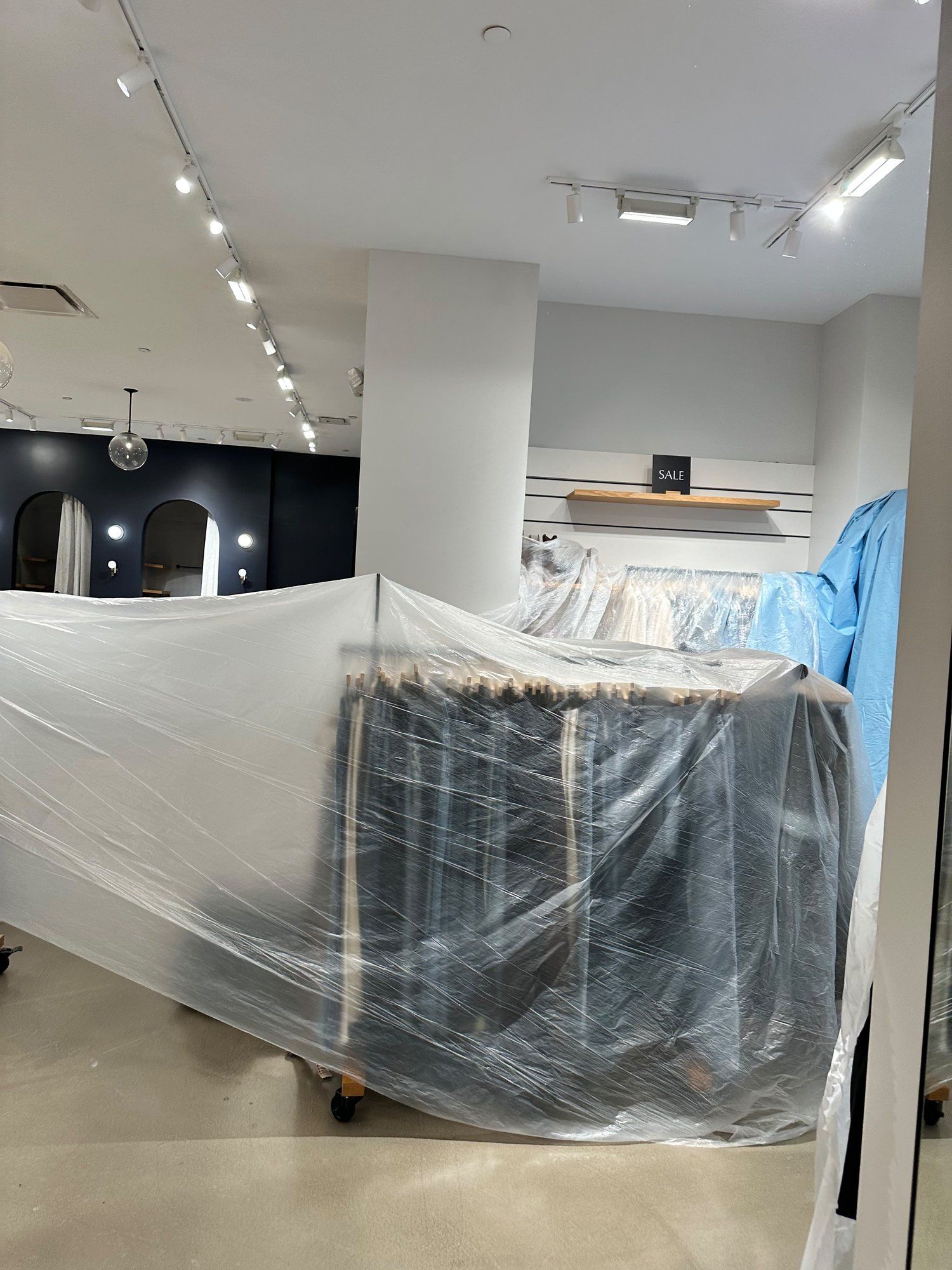 Clothing racks wrapped in protective plastic during store cleaning