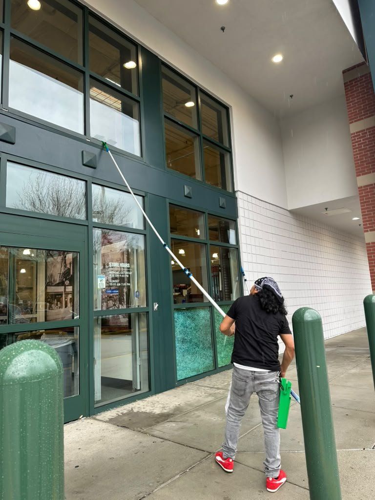 Window cleaning technician washing upper storefront glass with an extension pole